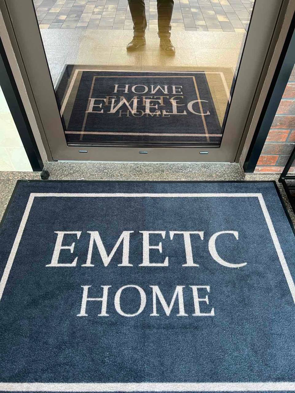 Темний придверний килимок з написом EMETC Home